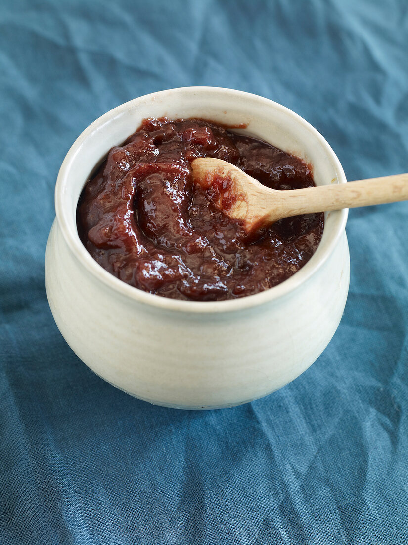 Plum jam in pot with wooden spoon