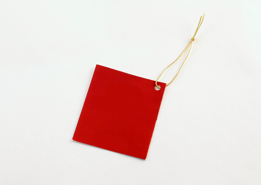 Red sticky note with golden thread on white background