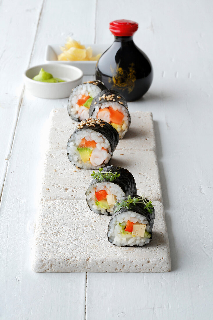 Pieces of avocado, tofu and sushi on serving dish