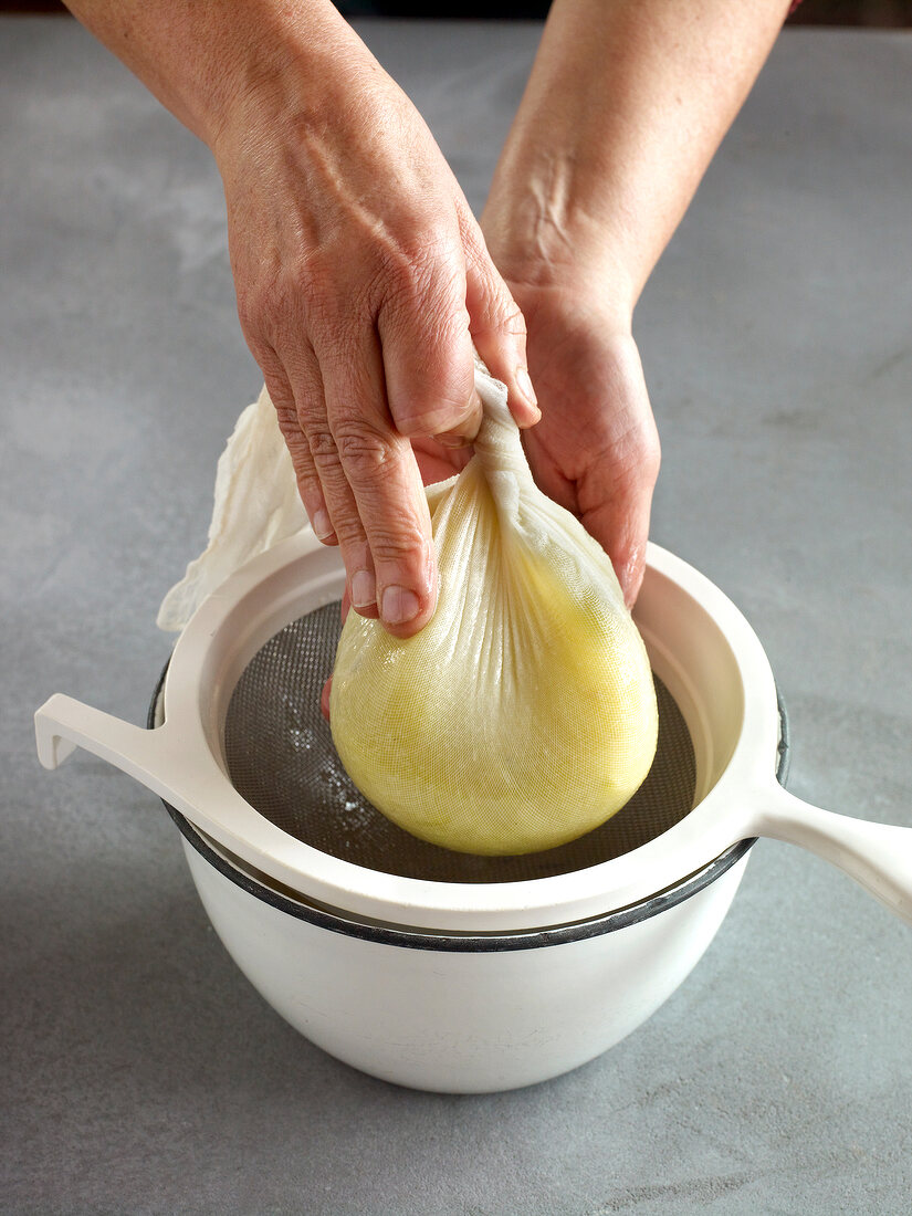 Close-up of squeezing liquid from jam tied in muslin cloth passed through strainer