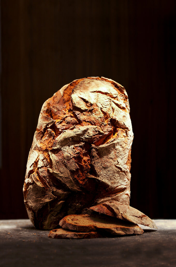 Loaf of bread on wooden surface against brown background