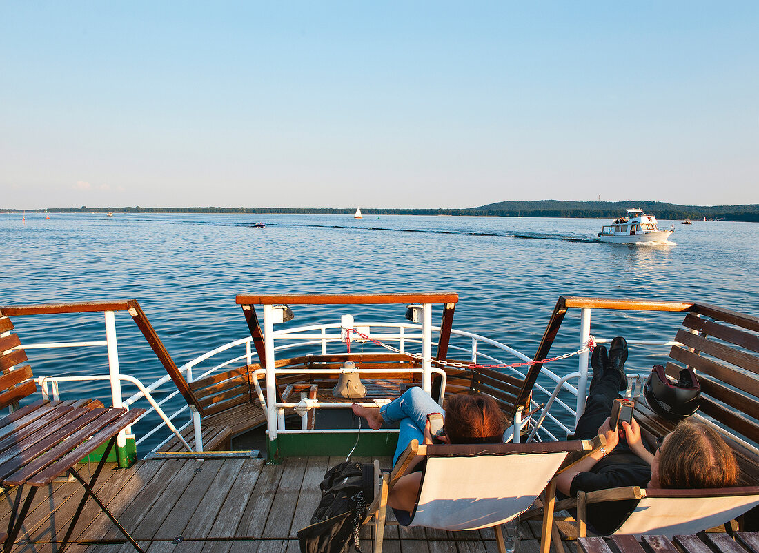 People relaxing on dock of ship in Muggelsee, Berlin, Germany