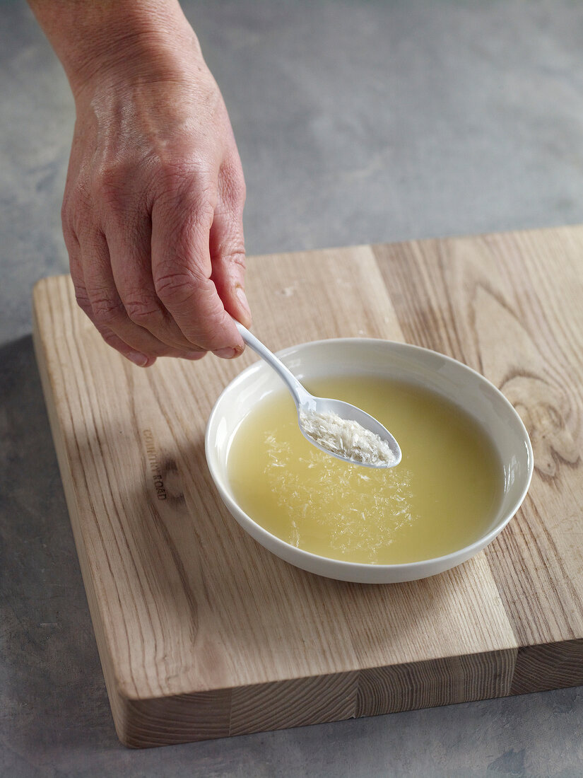 Close-up of adding agar-agar in bowl of pineapple juice and pulp for preparation of jam