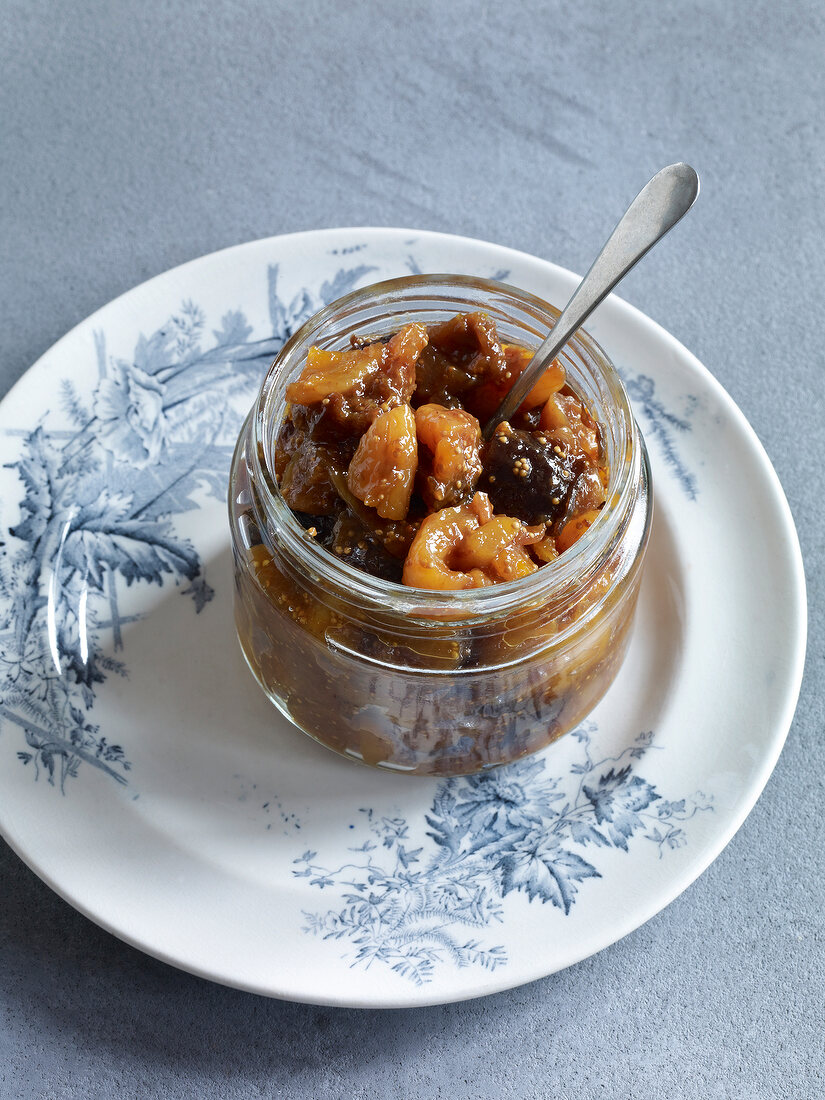 Dried fruit jam in jar with spoon on plate