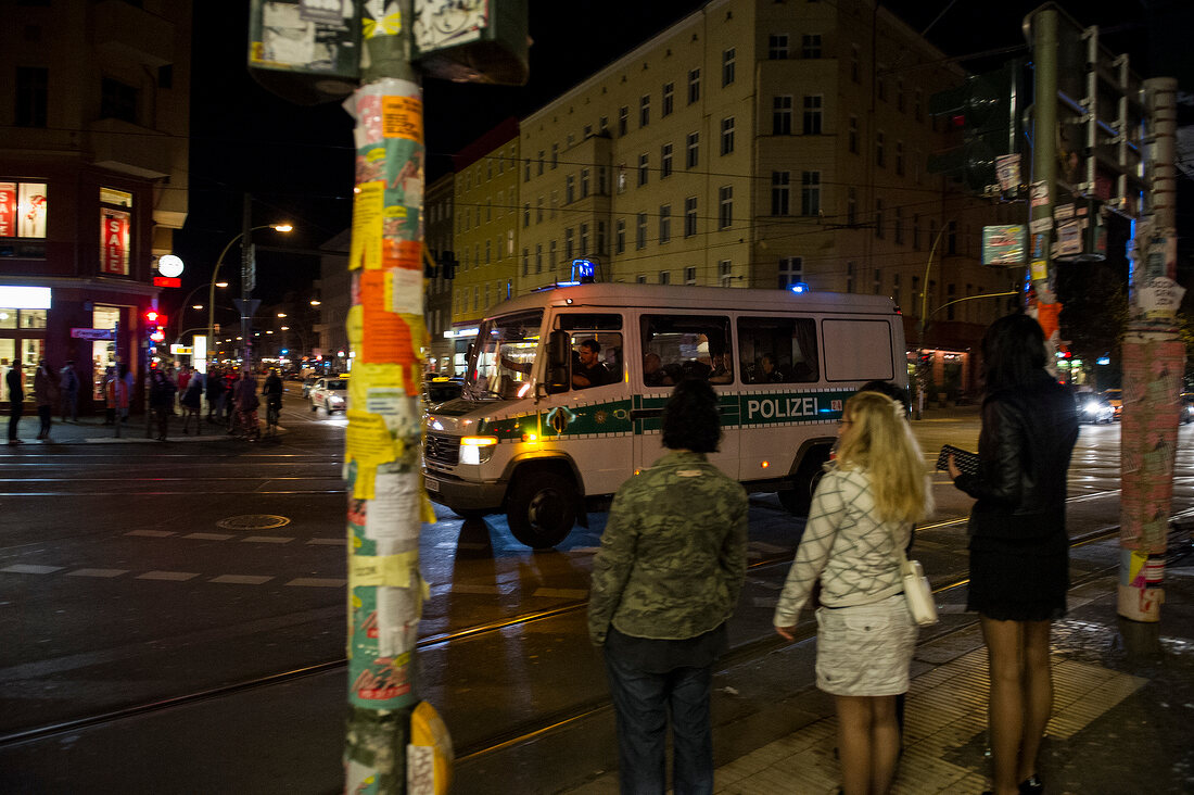 People and police van on street in Neukolln, Berlin, Germany