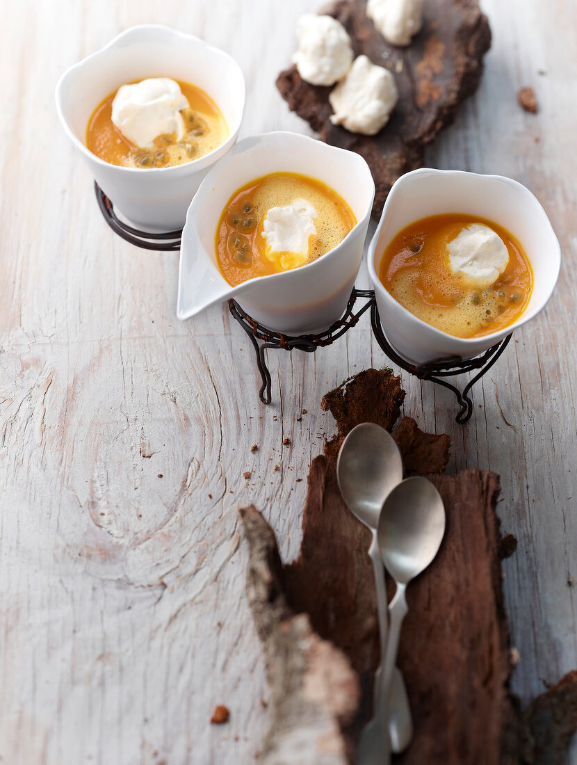 Passion fruit and carrot soup with coconut meringue on wood