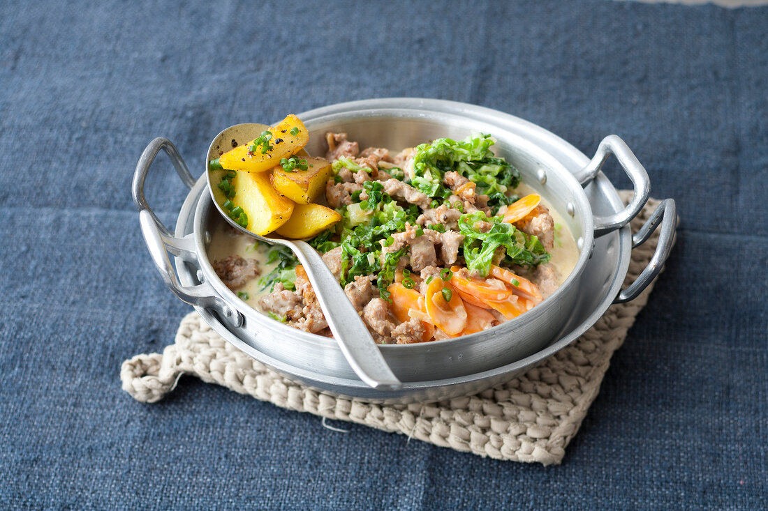 Ground pork and savoy in casserole with spoon on top