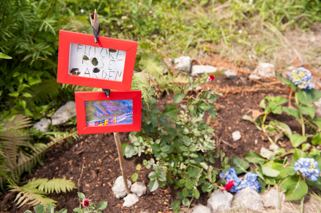 Name plate in middle of plants in garden in Schlesisches Tor, Berlin, Germany