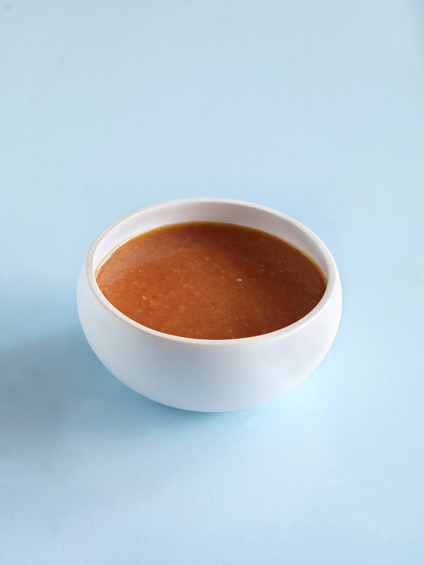 Bowl of spicy tomato ketchup on blue background