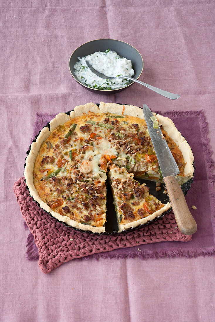 Ground pork and vegetable quiche on baking tray with knife