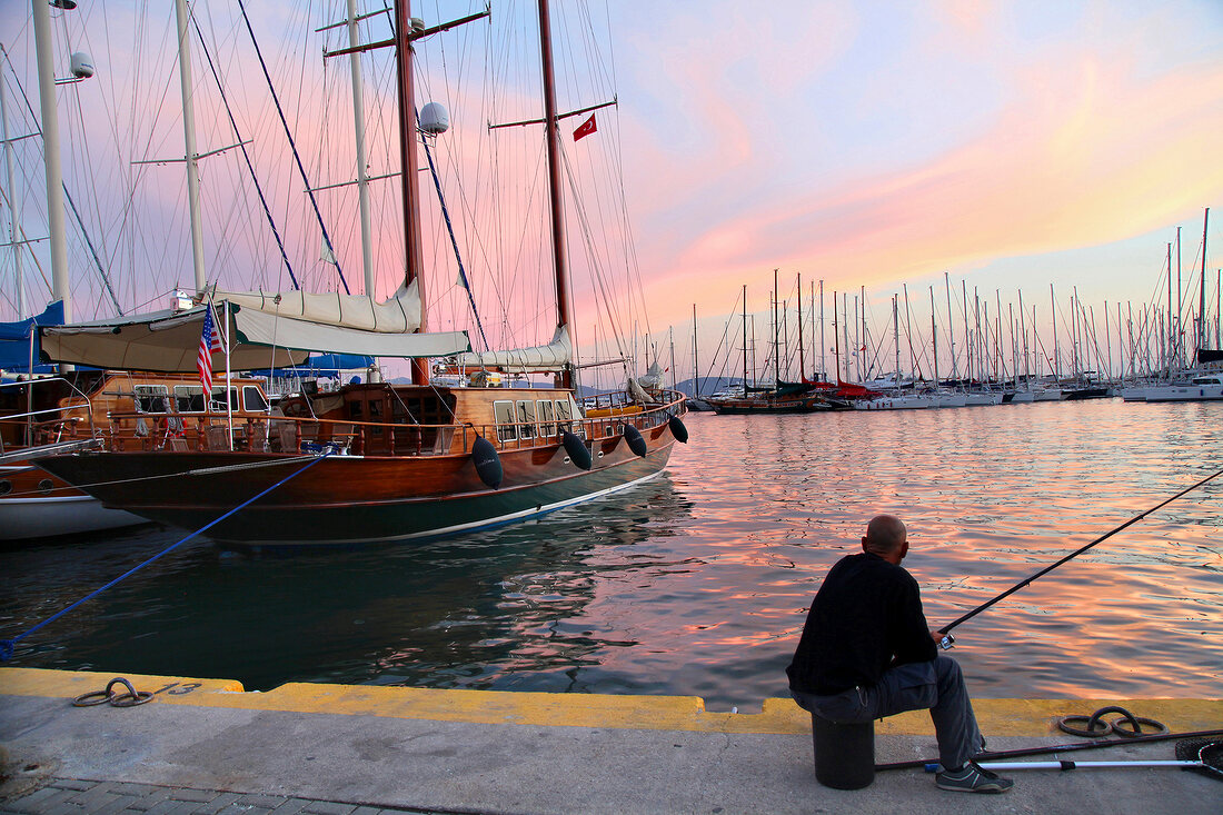 Man fishing at harbor at sunset in Bodrum Peninsula, Turkey