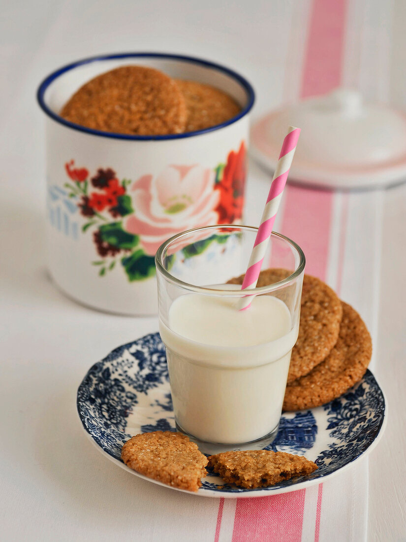 Three types of ginger cookies with glass of milk and straw