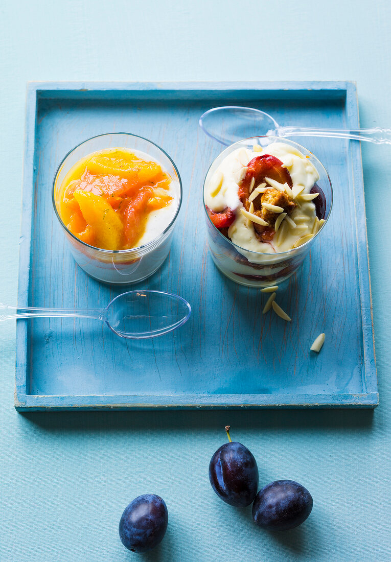 Citrus fruit jelly with vanilla yogurt and plum trifle in glass on blue tray