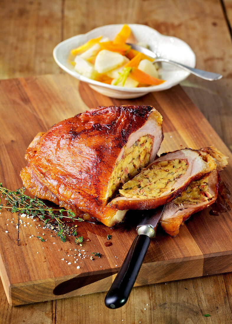 Slices of stuffed veal breast with carrots and celery on wooden board