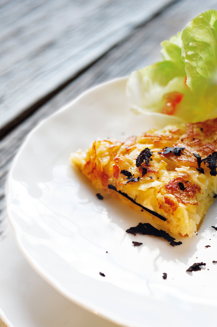 Close-up of rosti with goat cheese topped with pomegranate and lettuce leaves on plate