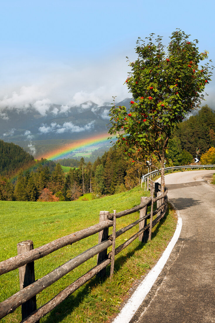 View of road and La Val rainbow in village Wengen, South Tyrol, Italy