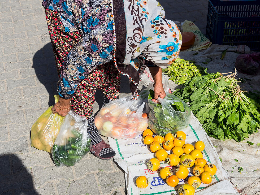 Woman picking up vegetables in weekly market in Yazikent, Aegean, Turkey