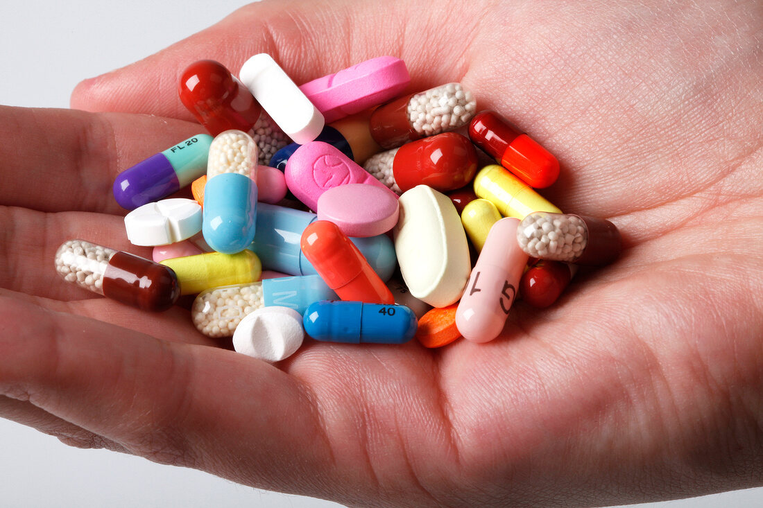Close-up of pills and tablets in hand on white background