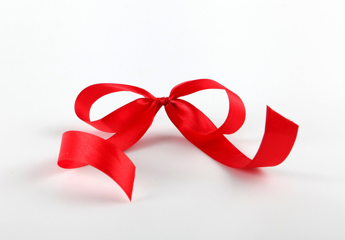 Close-up of red satin bow on white background