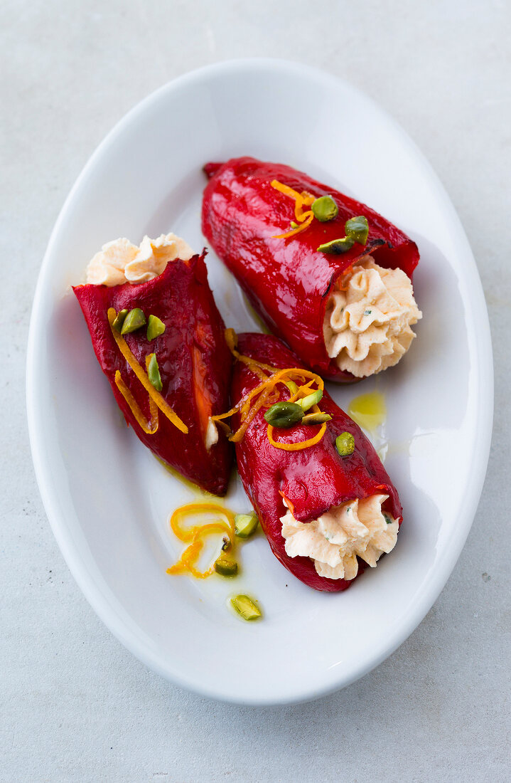 Red peppers stuffed with cream cheese and garnished with pistachios on plate