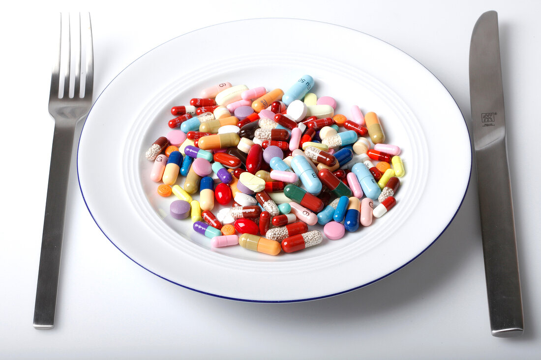 Close-up of various colourful tablets on a plate with knife and fork next to it