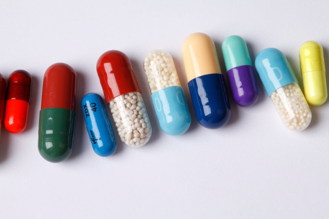 Various coloured capsules arranged in a row on white background