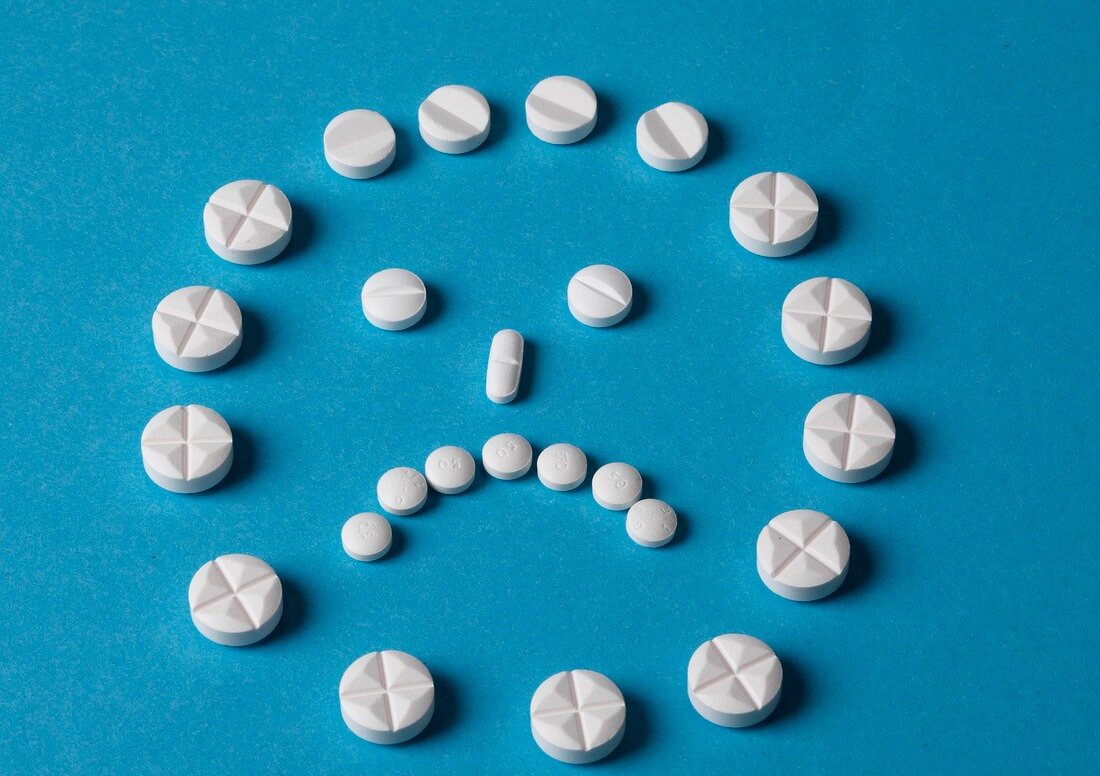 Close-up of sad smiley made with white tablets on blue background