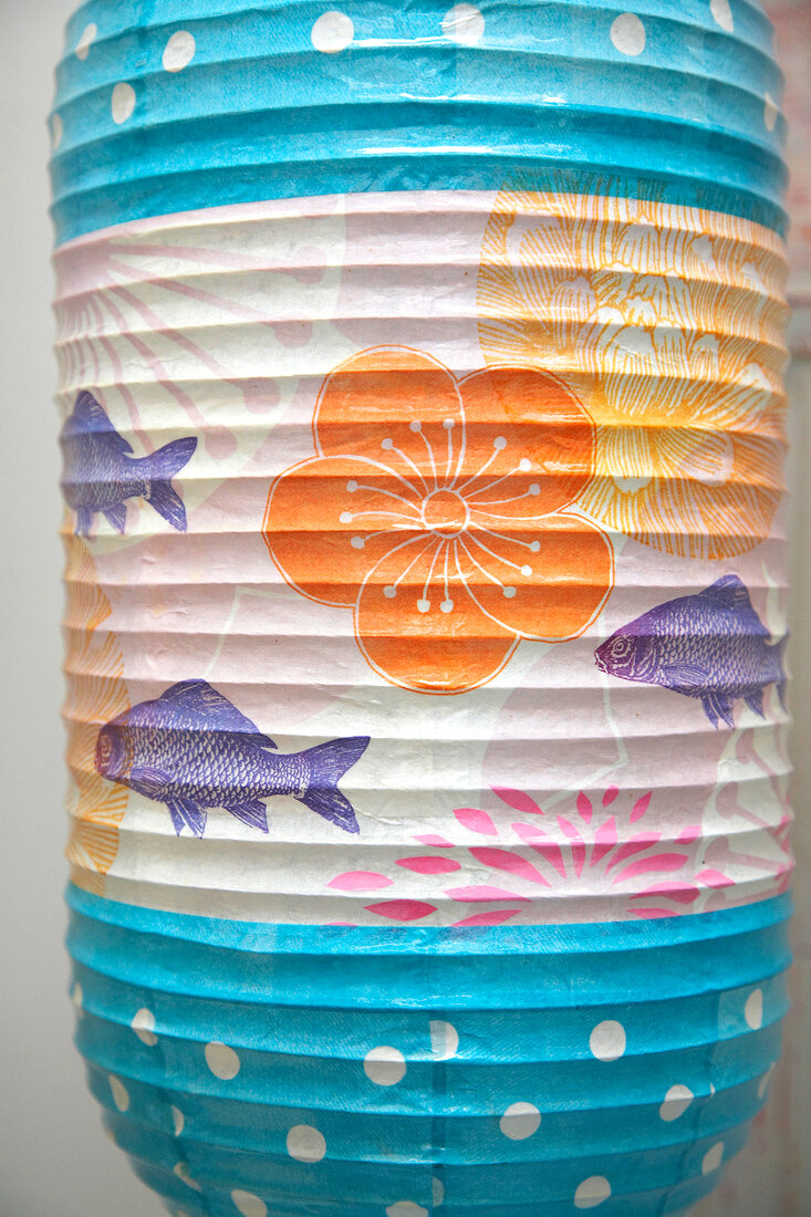 Close-up of person painting colourful lantern with flower and fish motif