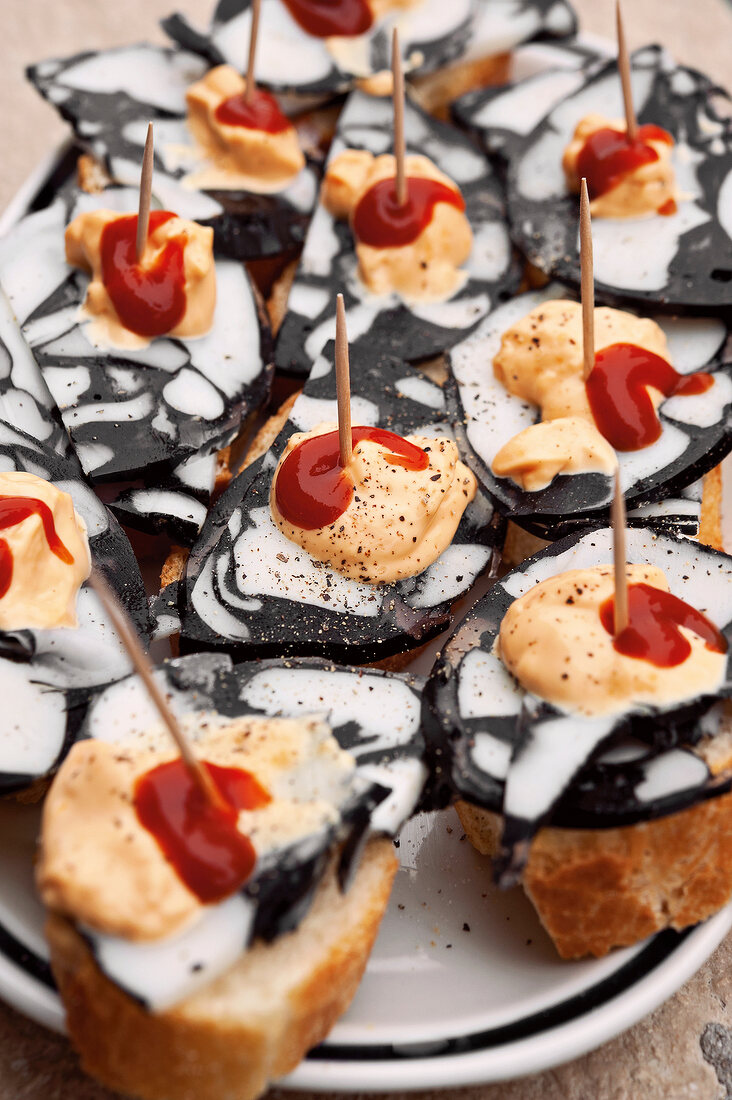 Close-up of skewers of bread with octopus terrine topped with mayonnaise and ketchup