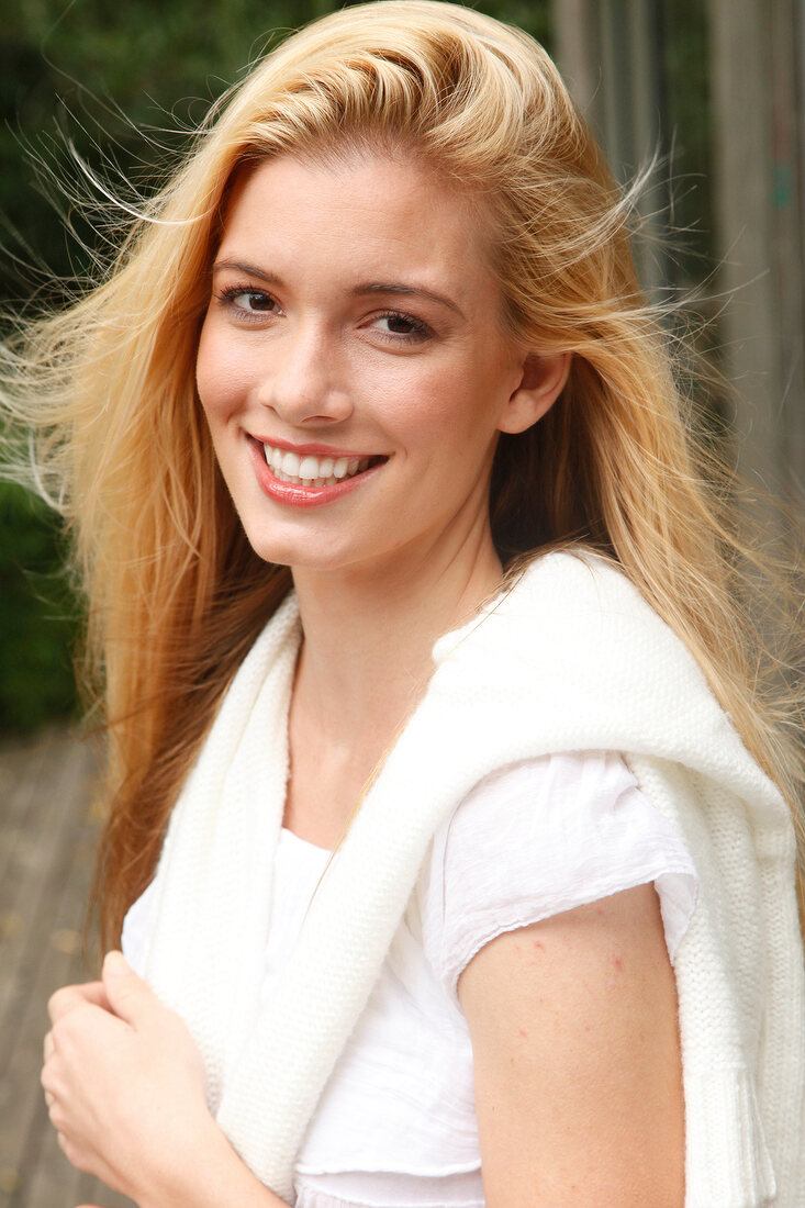 Portrait of beautiful blonde woman with long hair wearing purple top, smiling
