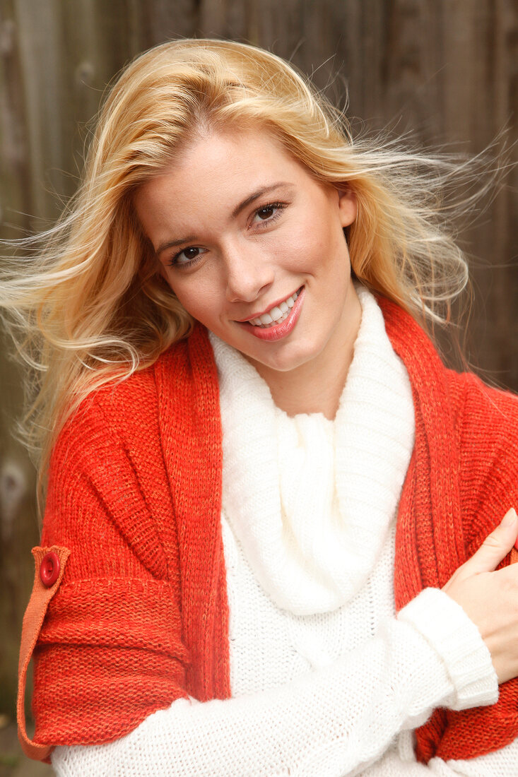 Portrait of beautiful blonde woman with long hair in white and orange cardigan, smiling