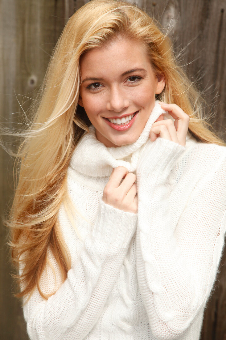 Portrait of beautiful blonde woman with long hair in white turtleneck sweater, smiling