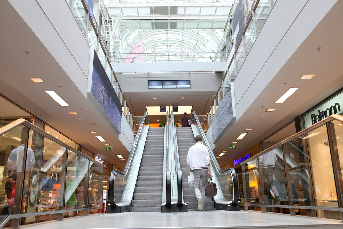 ein Mann betritt die Rolltreppe in einem Kaufhaus