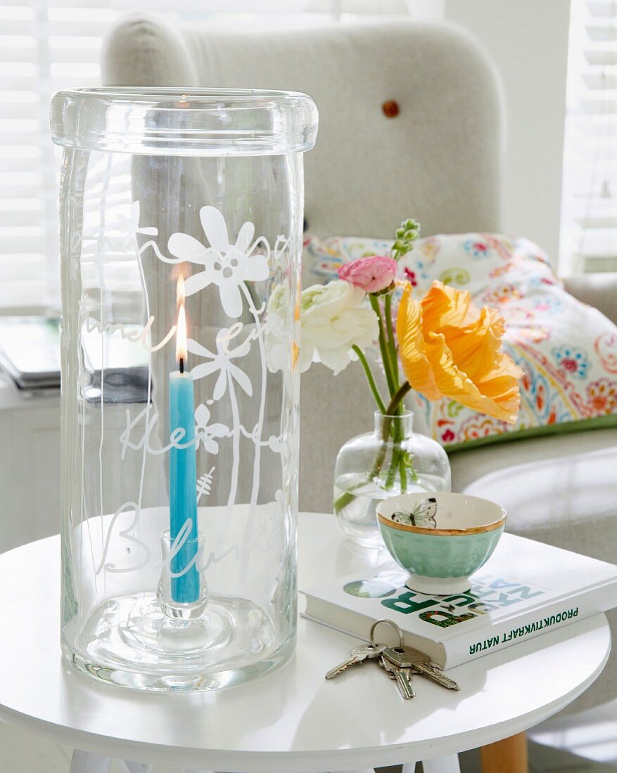 A tall, glass, hand-engraved lantern on a side table