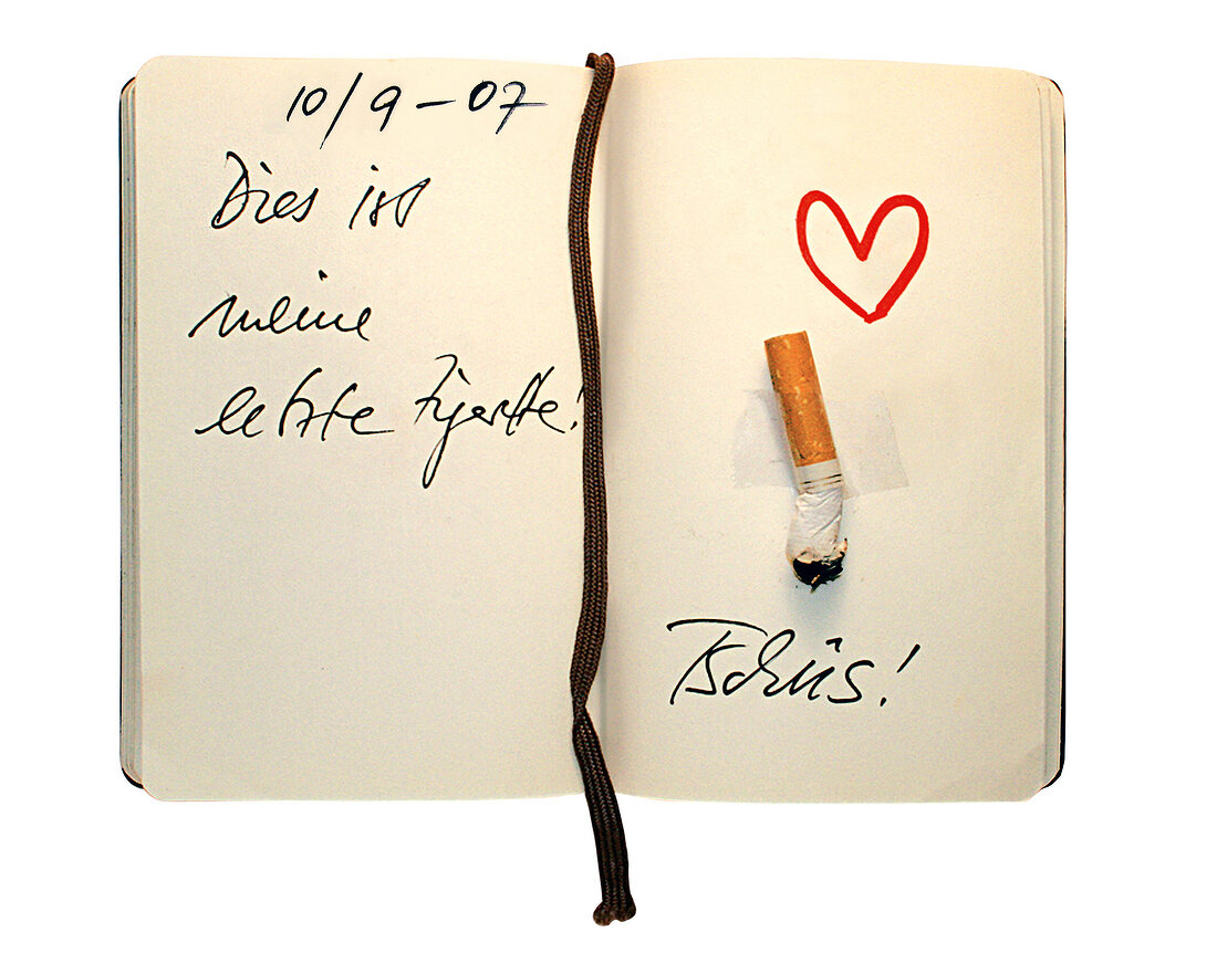 aufgeschlagenes Notizbuch mit ausgedrückter Zigarette und Herz