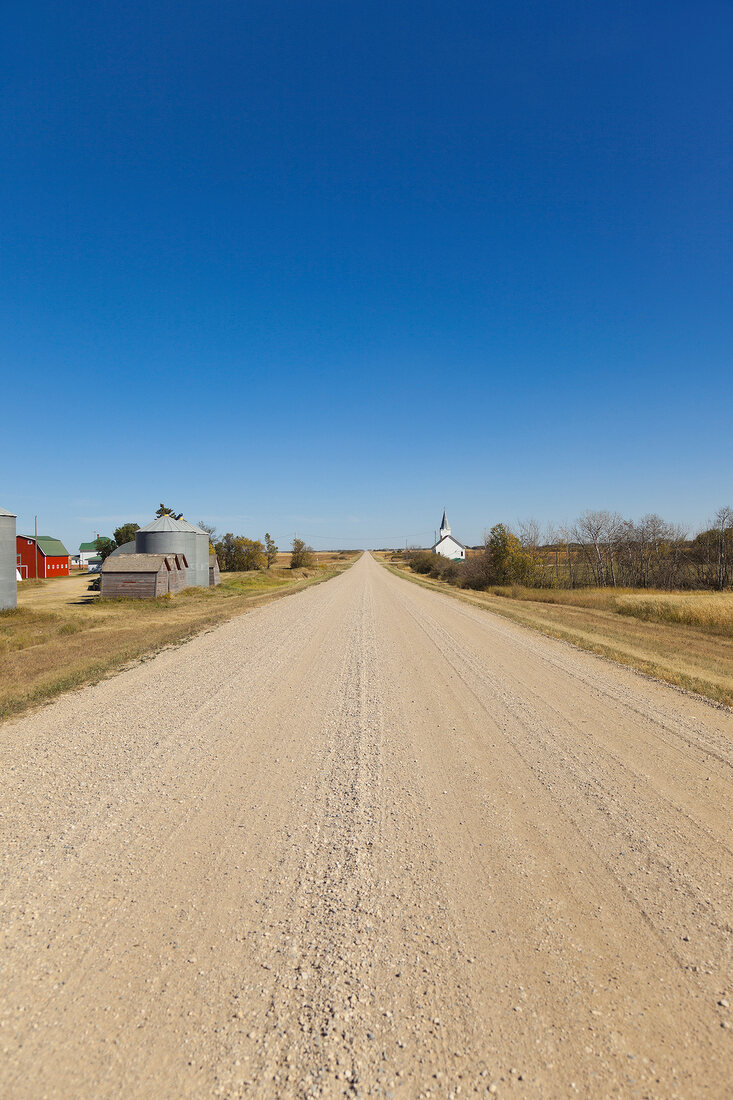View of empty Highway 731 with farm House and Church, Saskatchewan, Canada