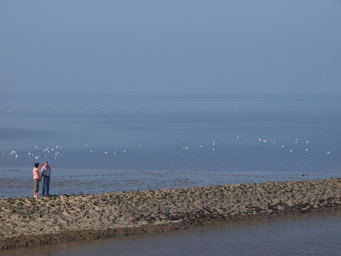 People standing near Wadden sea at Neuharlingersiel, Lower Saxony, Germany