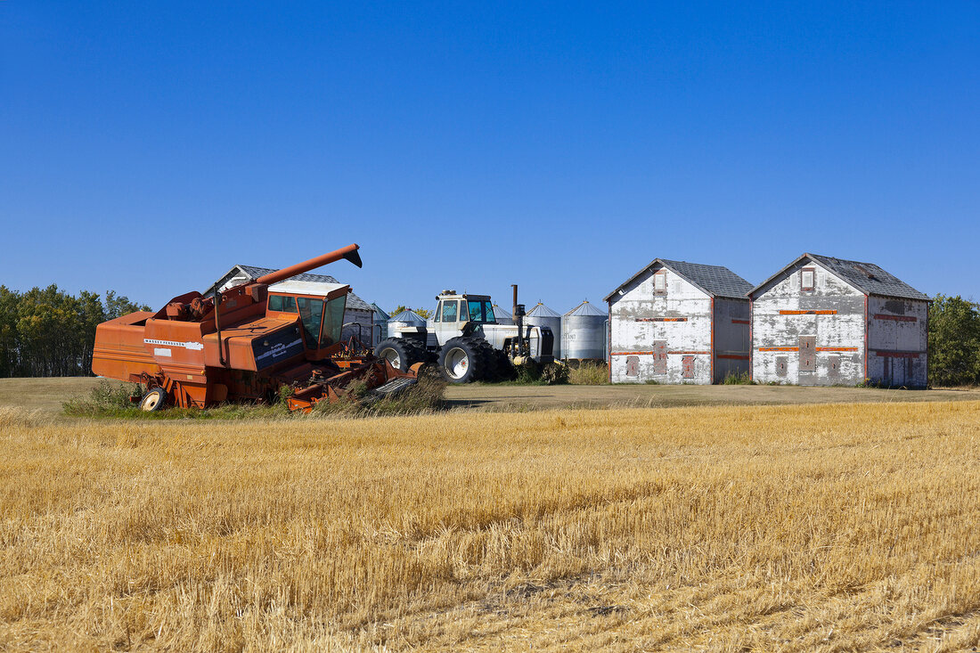 View of harvester in landscape with garnary on Highway 6, Saskatchewan, Canada