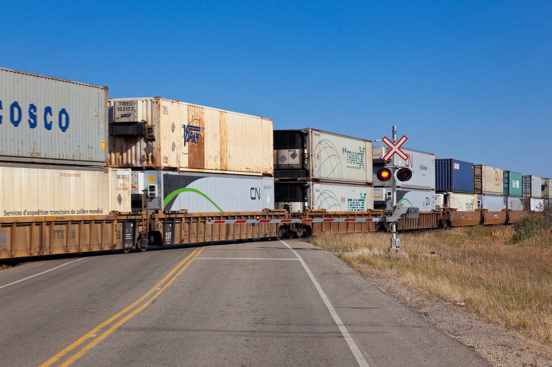 View of cargo train crossing railroad on Highway 15, Saskatchewan, Canada