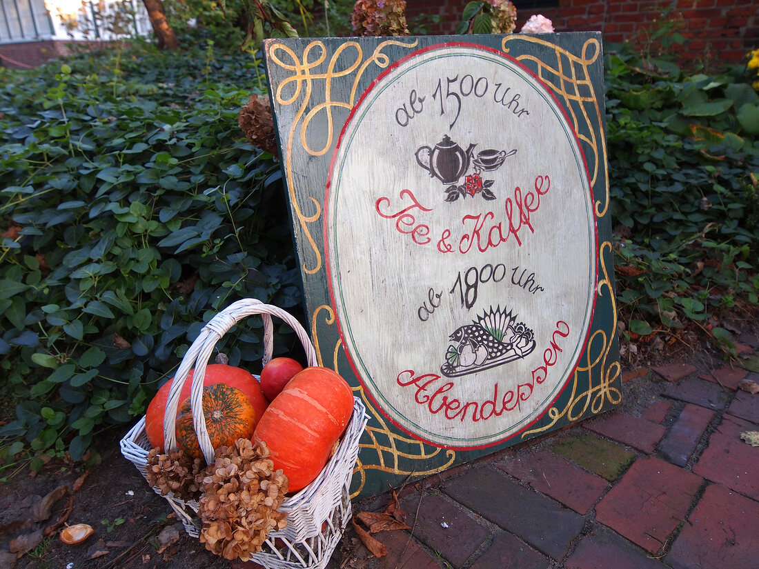 View of Spiekeroog restaurant sign post and pumpkin in basket, Lower Saxony, Germany