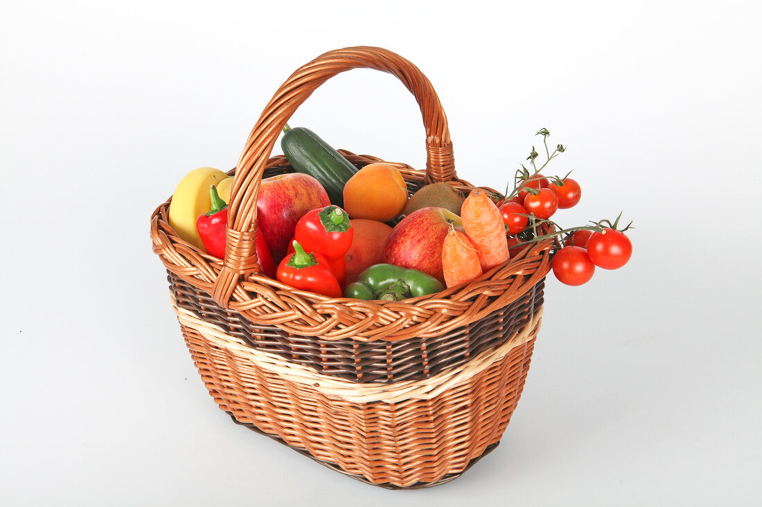 Basket of fruit and vegetables on white background