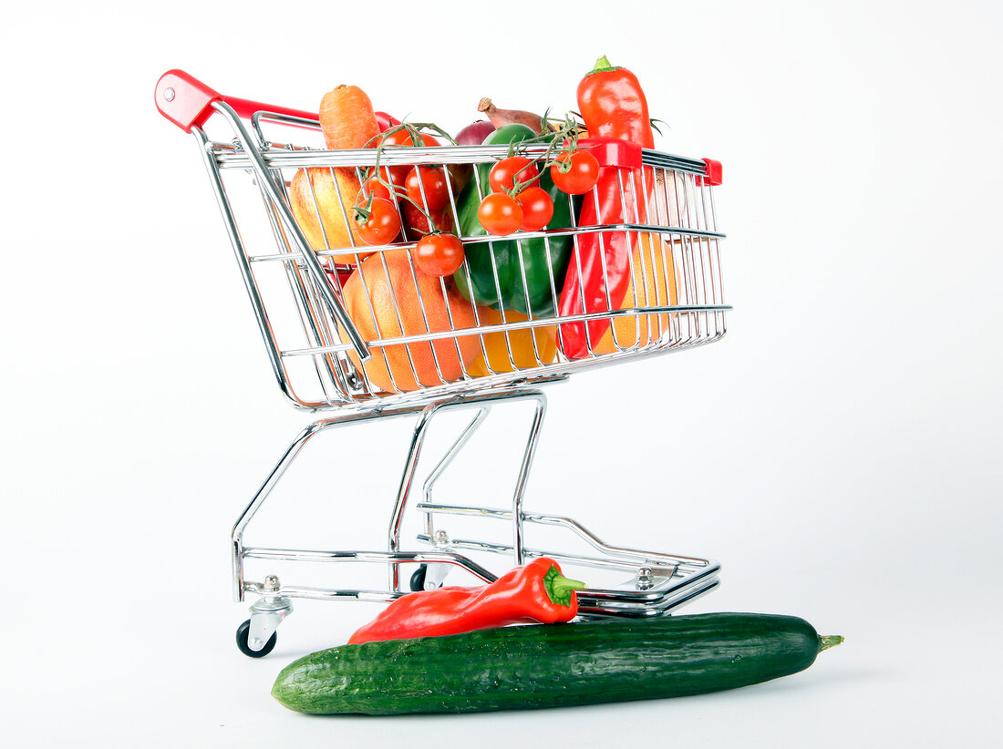 Shopping cart with vegetables and fruits on white background