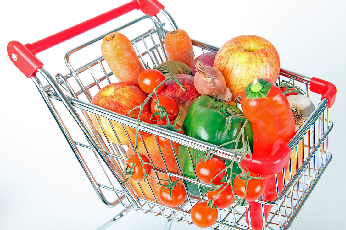 Shopping cart with vegetables and fruits on white background