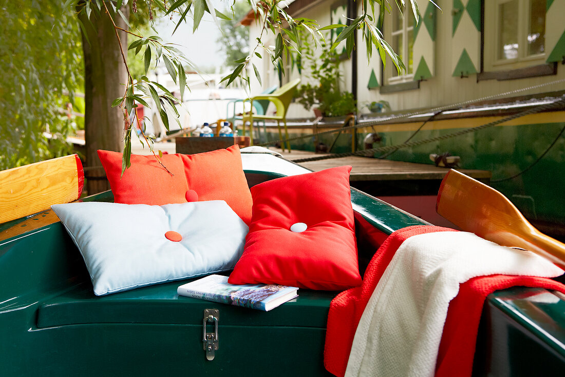 Green rowing boat with pillows, blankets and book