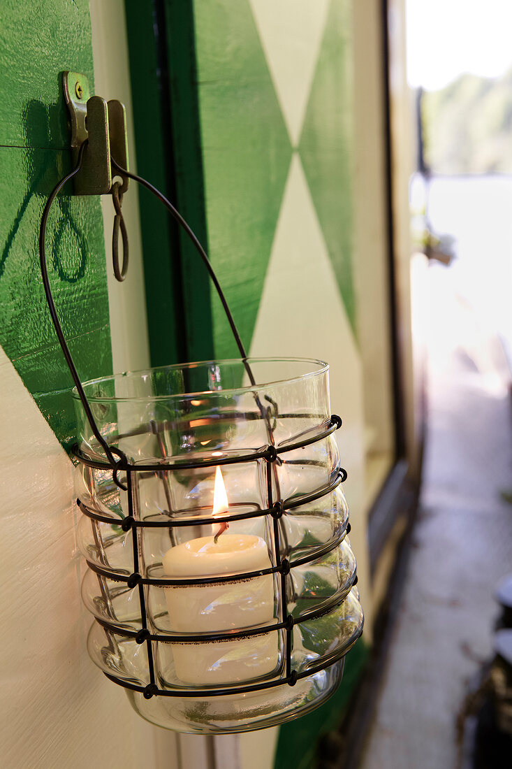 Lit candle in glass lantern with metal frame