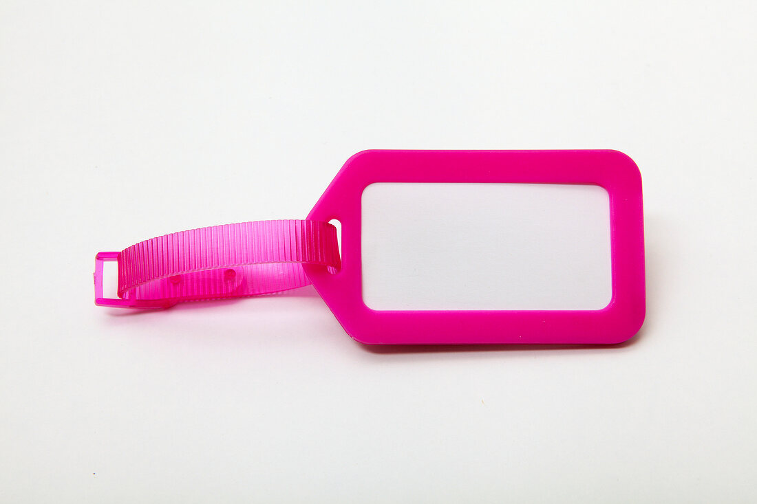 Close-up of blank pink luggage tag on white background