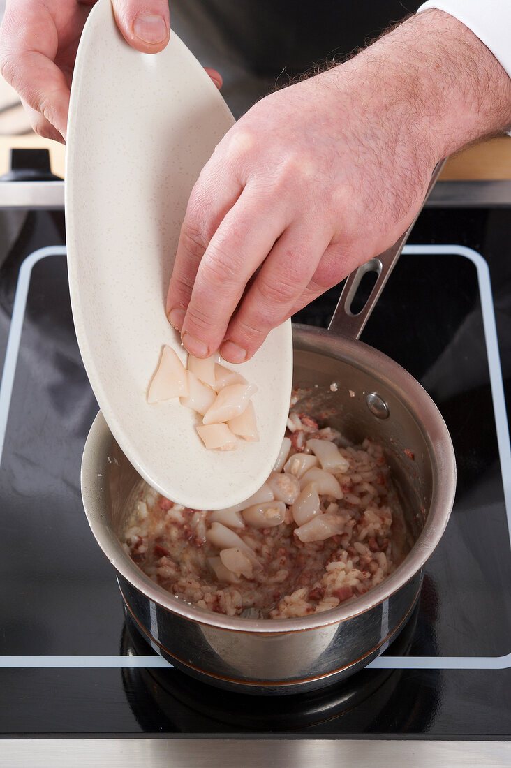 Adding chopped pieces of razor clams to mixture in saucepan