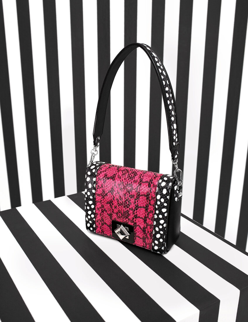 Pink and black bag with white dogs against black-white striped surface