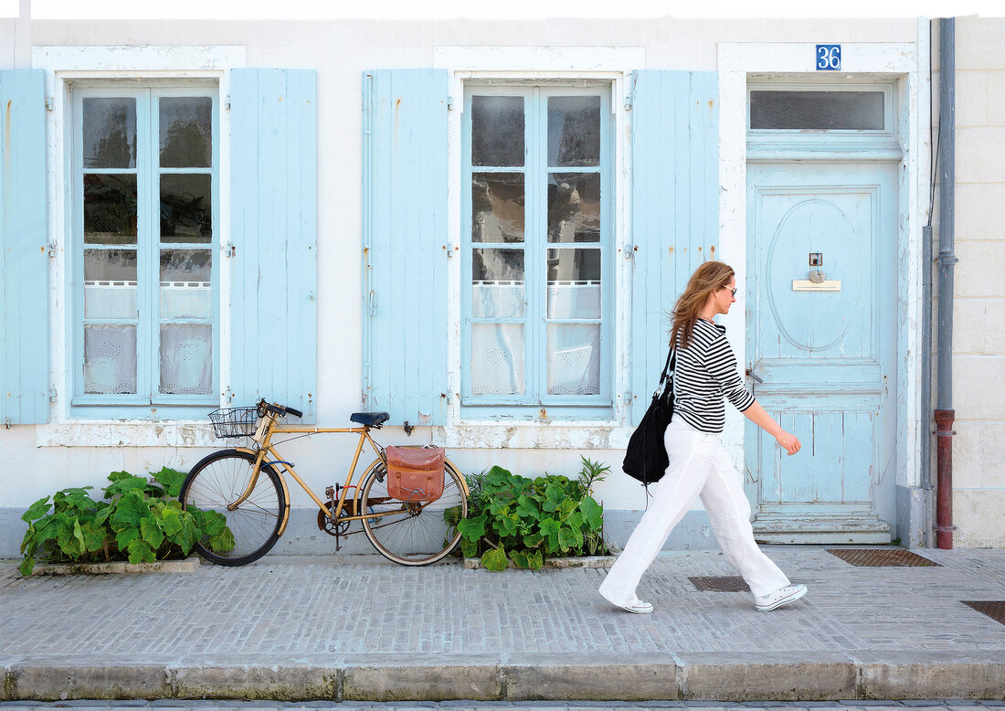 Women walking on street passing through house, Ile de Re, France