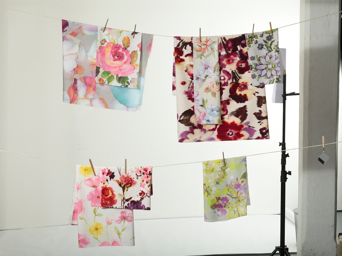 Variety of table cloth with floral print hanging on cloth line